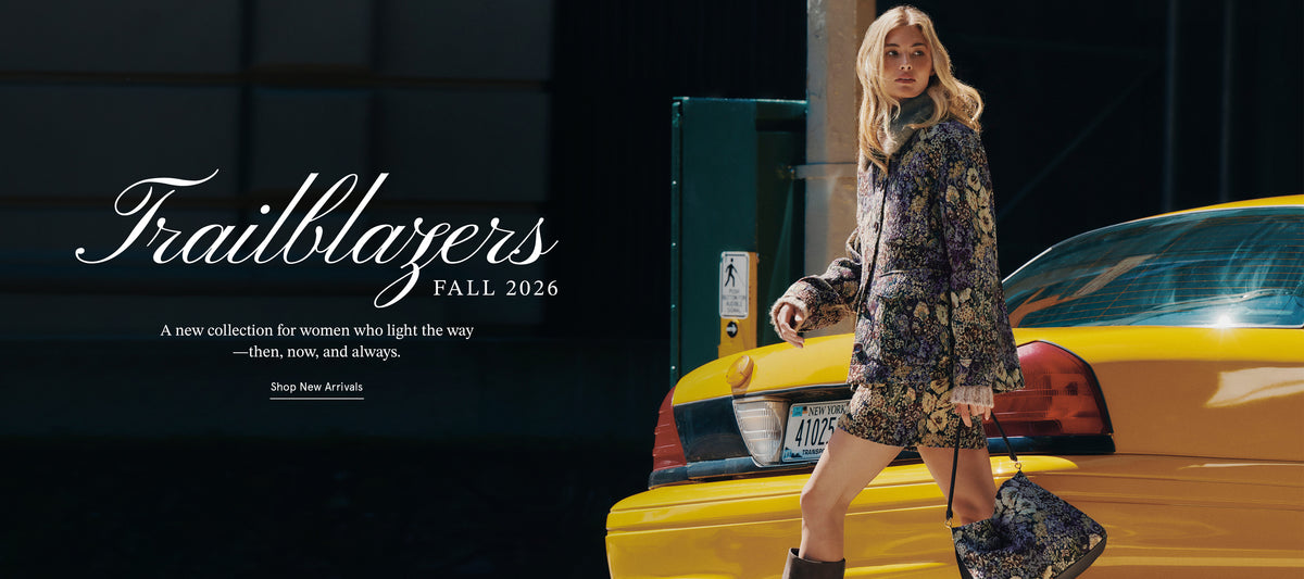 A blonde woman in a patterned coat and skirt walks past a yellow taxi against a dark, urban background.