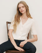 Veronica Beard Cream ribbed knit short-sleeve cardigan with a V-neck and large white buttons.