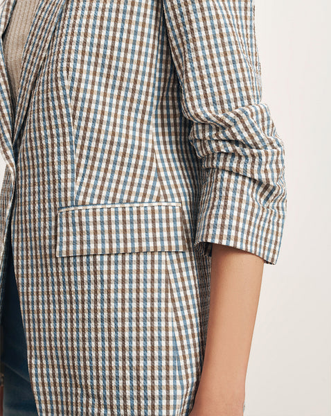 A close-up view of a person's arm wearing a checkered jacket, with the background appearing to be a plain, light-colored surface.