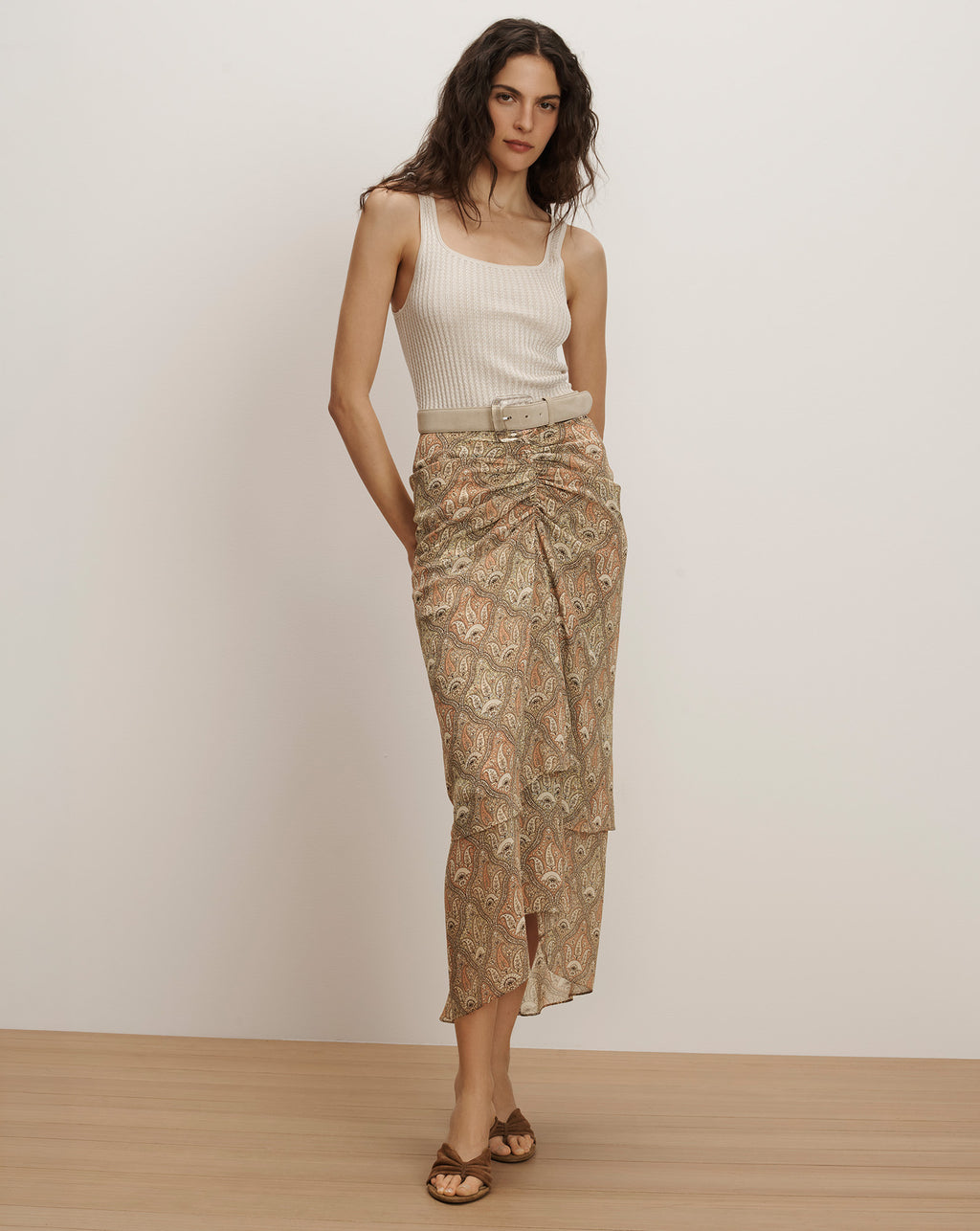 Veronica Beard Ribbed cream tank top and a sheer, ruched midi skirt with a beige paisley print and a matching belt.