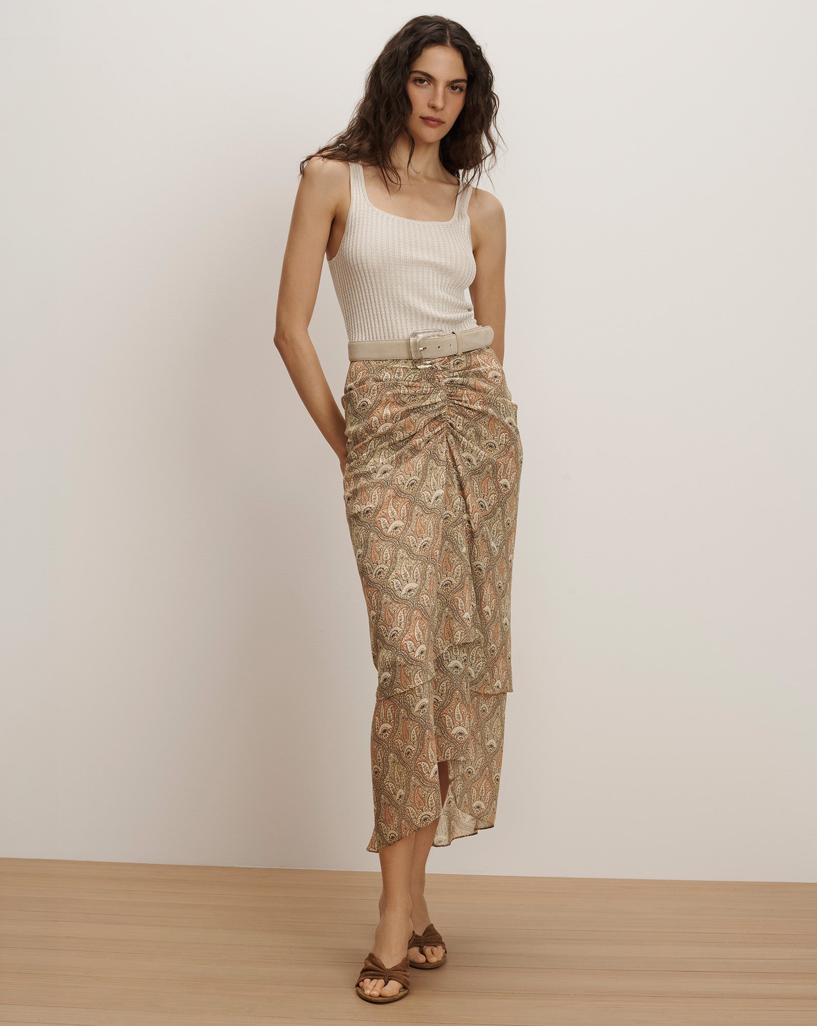 Veronica Beard Ribbed cream tank top and a sheer, ruched midi skirt with a beige paisley print and a matching belt.
