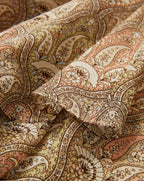 Veronica Beard Ribbed cream tank top and a sheer, ruched midi skirt with a beige paisley print and a matching belt.