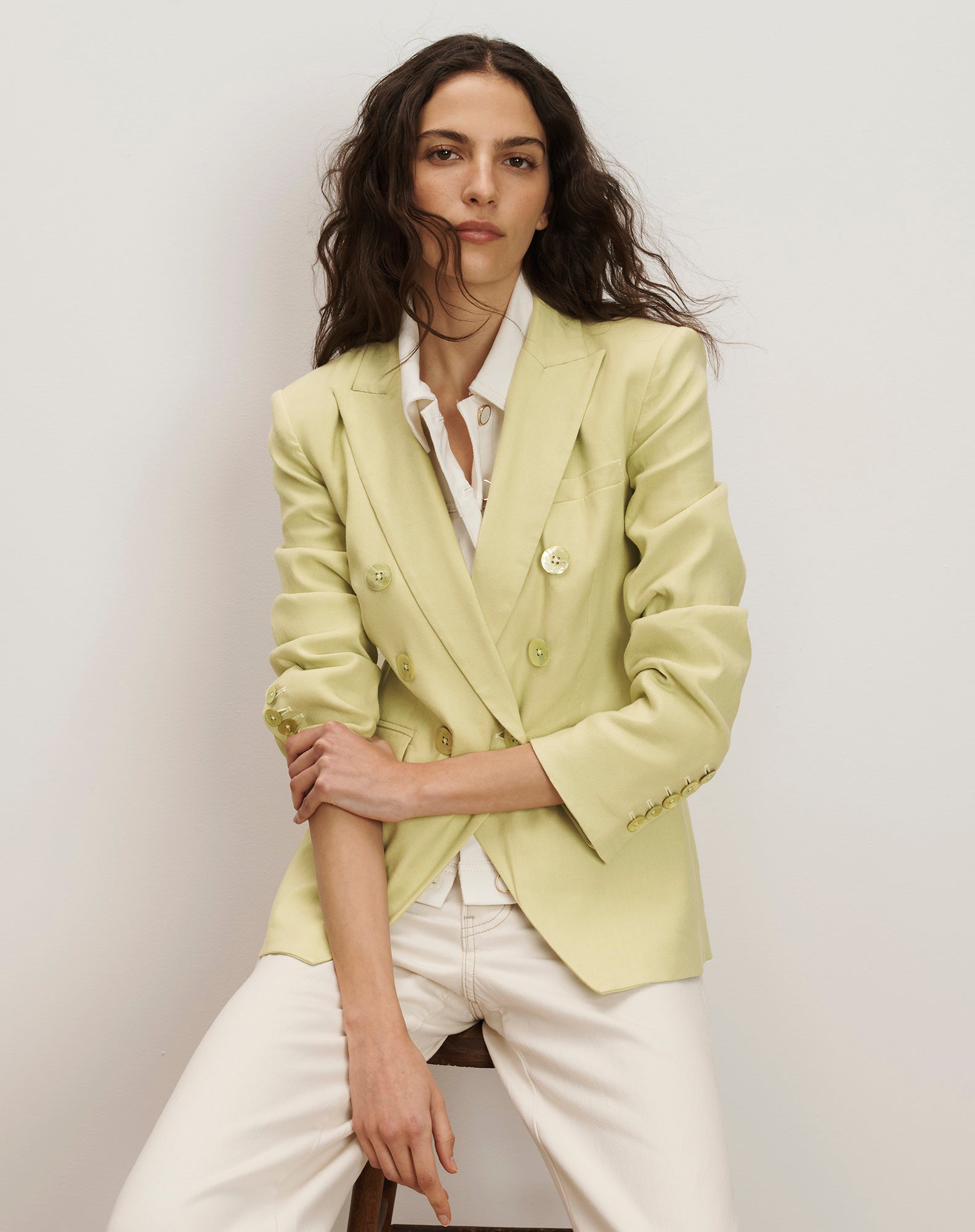 Veronica Beard Light green double-breasted blazer with peak lapels, paired with a white button-down shirt and off-white trousers.