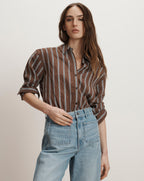 Veronica Beard Brown and white striped button-down shirt with rolled sleeves, paired with light wash denim jeans.