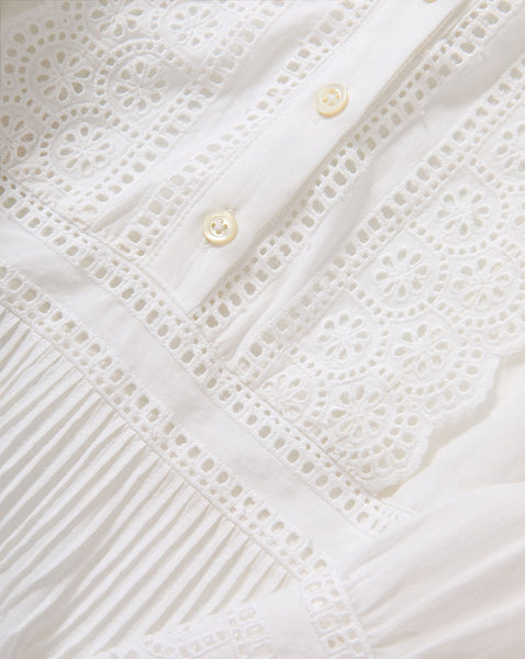 The image depicts a delicate, intricate pattern of lace and pleats, creating a visually striking and textured white fabric.