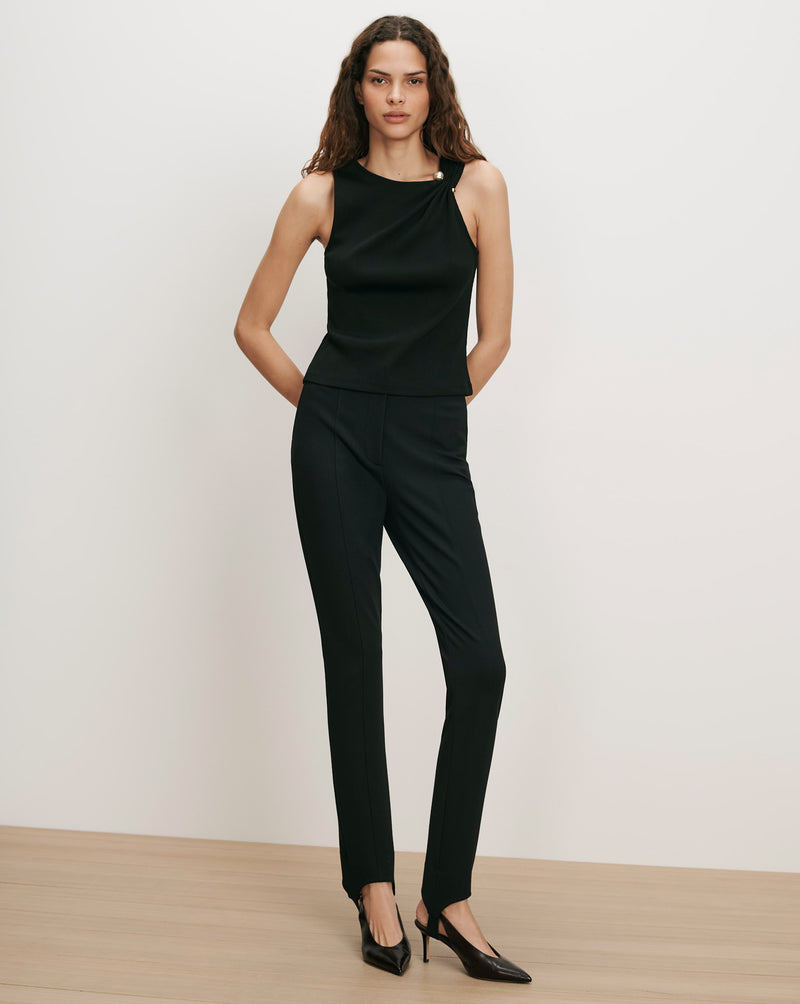 Veronica Beard Black sleeveless top with gold button, black slim pants.