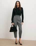 Veronica Beard Black silk bow blouse, gray wool trousers, black leather handbag.