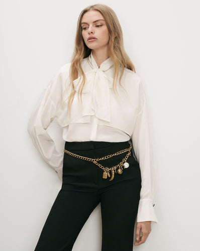 Veronica Beard White silk blouse, black trousers, gold chain belt.