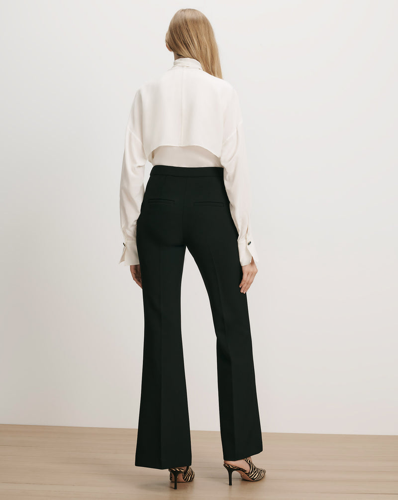Veronica Beard Black flared trousers, white long-sleeve blouse.