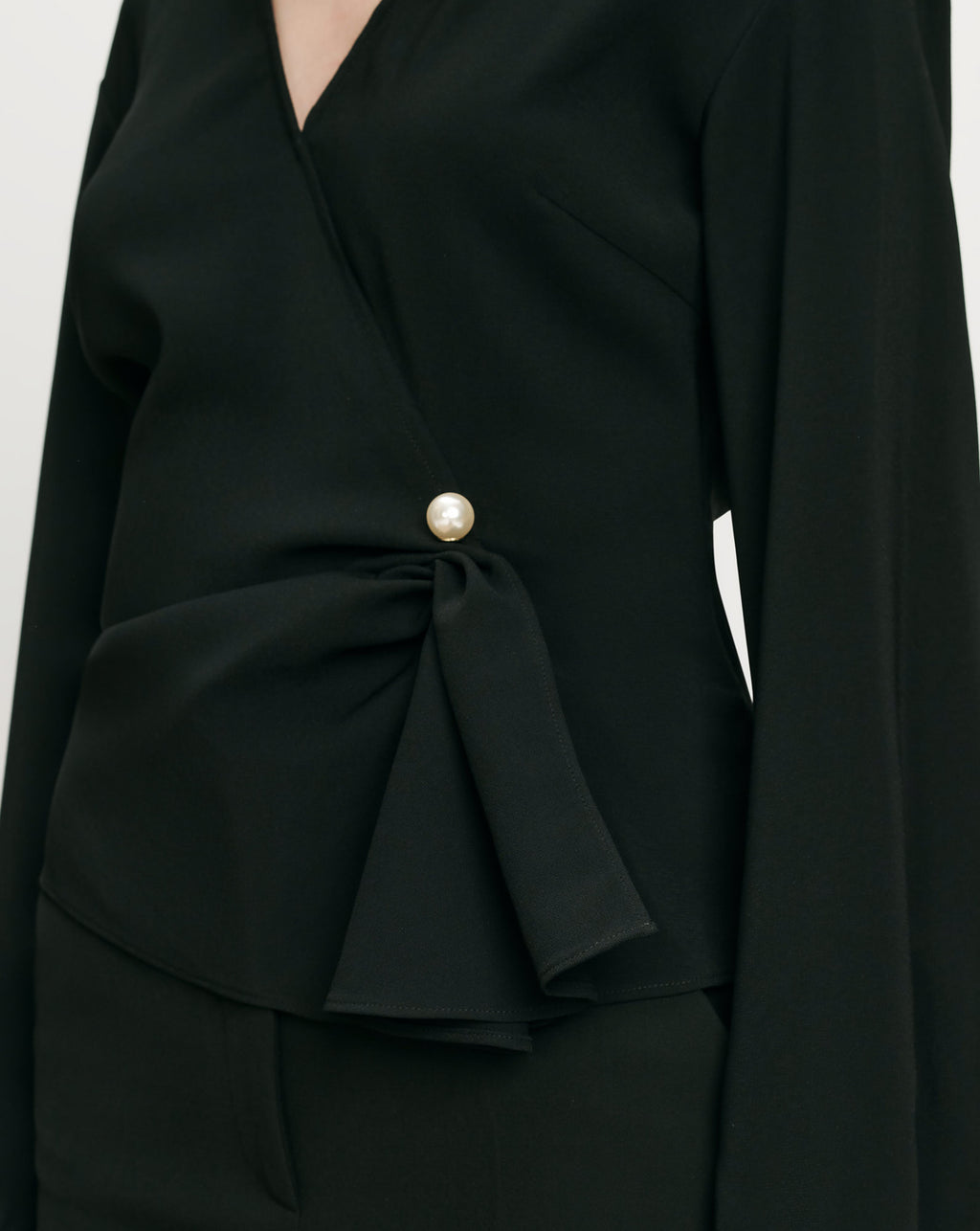 Veronica Beard Black wrap blouse with pearl button and draped detail.