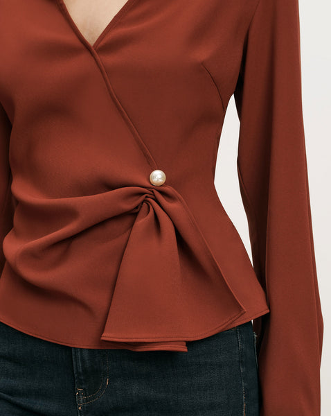 Veronica Beard Rust wrap blouse with pearl button.