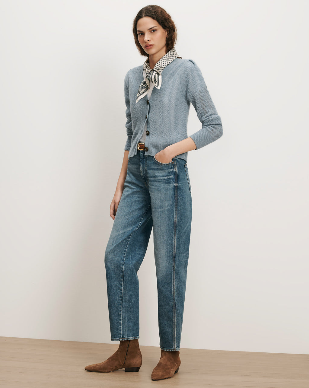 Veronica Beard Blue cable knit cardigan, jeans, brown boots, and patterned scarf.