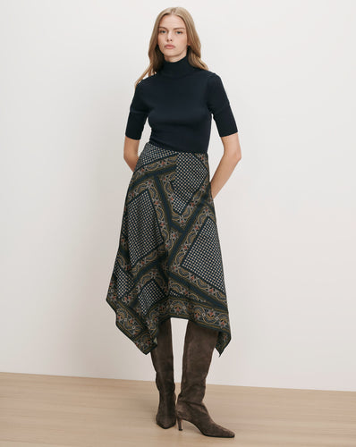 Veronica Beard Black ribbed turtleneck, patterned handkerchief hem skirt, brown suede boots.