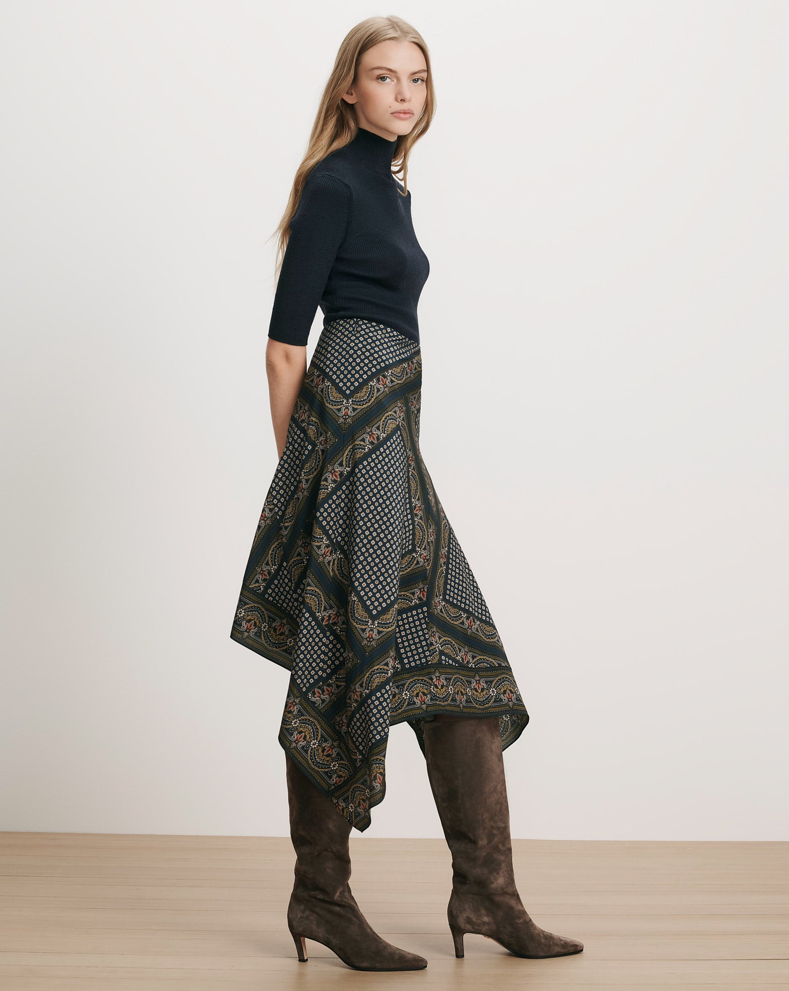 Veronica Beard Black turtleneck, patterned handkerchief skirt, brown suede boots.