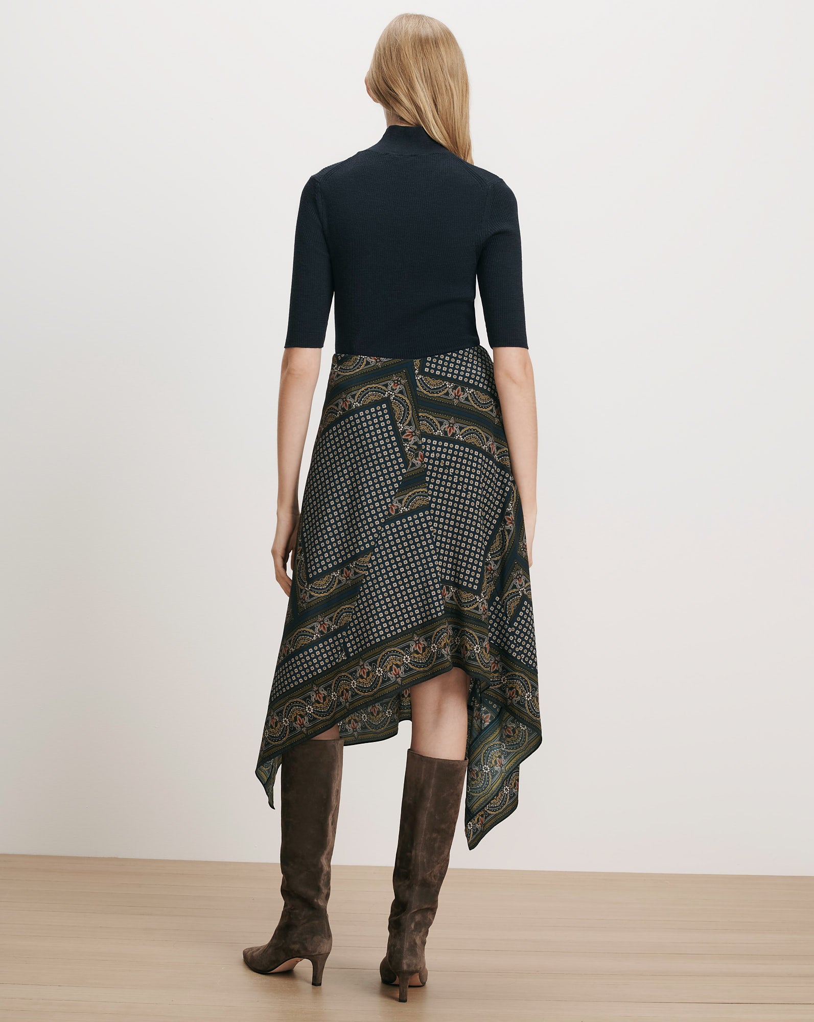 Veronica Beard Black ribbed top, patterned handkerchief skirt, brown suede boots.