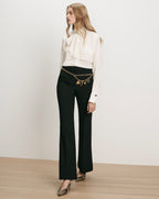 Veronica Beard White silk blouse, black flared trousers, gold chain belt.