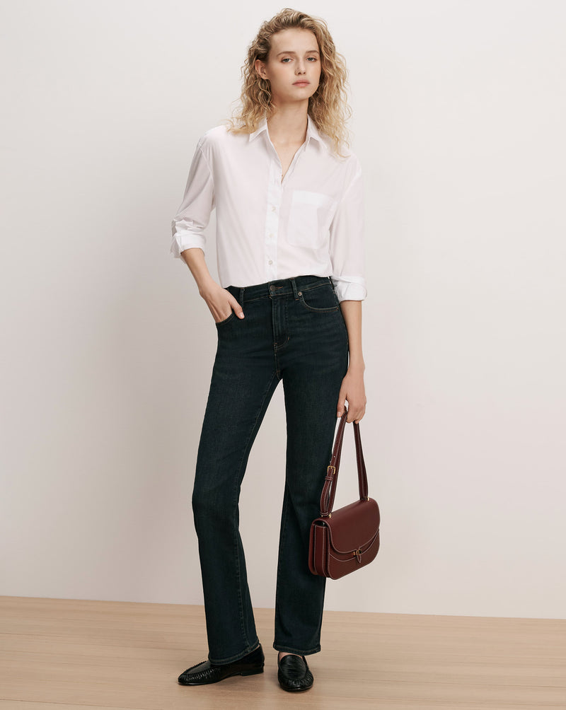 Veronica Beard White button-down shirt, dark wash jeans, brown leather bag.