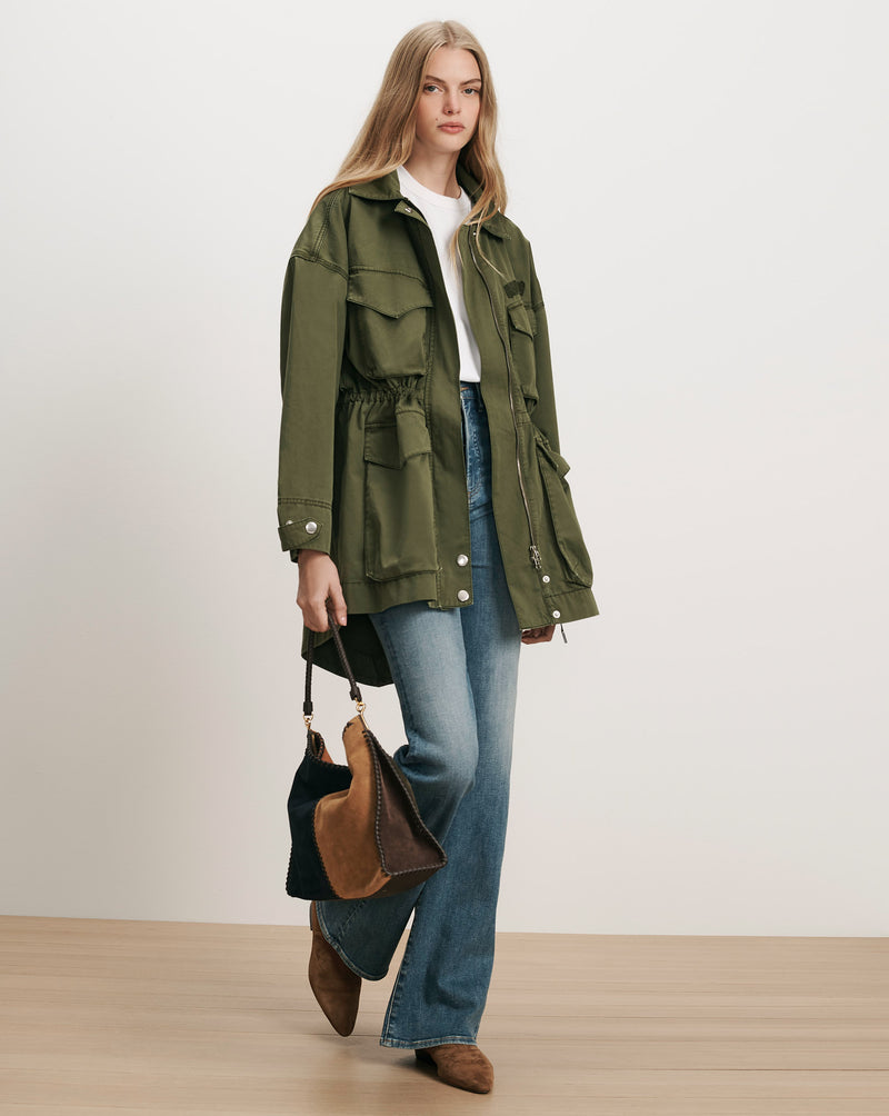 Veronica Beard Olive green utility jacket, white t-shirt, blue jeans.