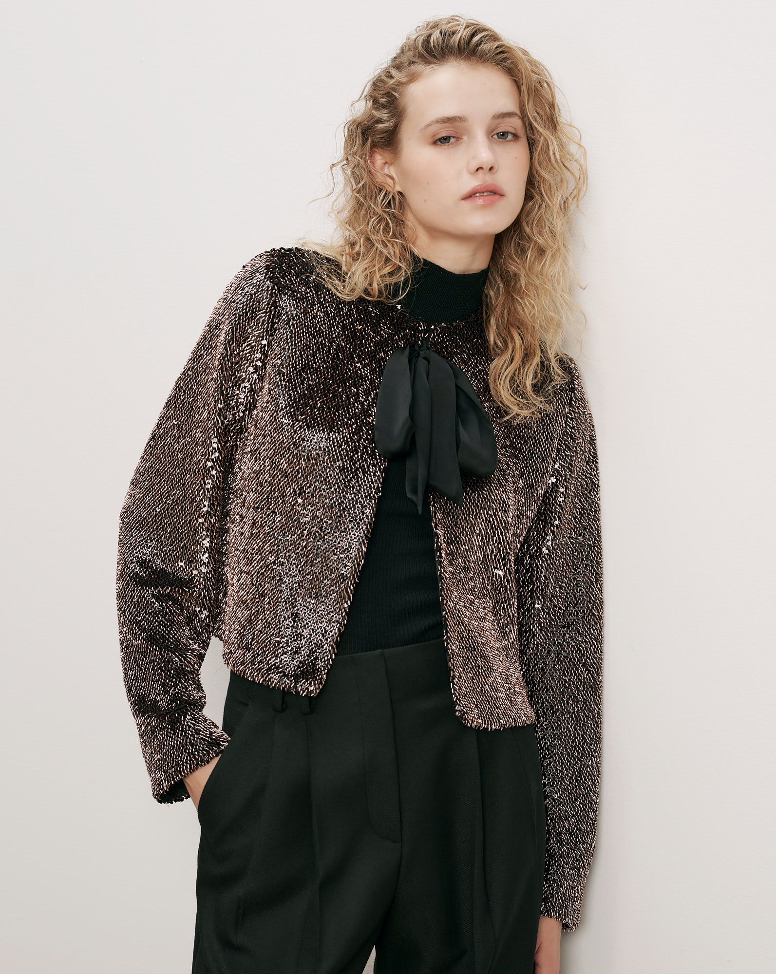 Veronica Beard Bronze sequin jacket, black turtleneck, and black trousers.