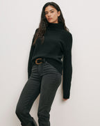 Veronica Beard Black turtleneck sweater, dark gray jeans, black belt.