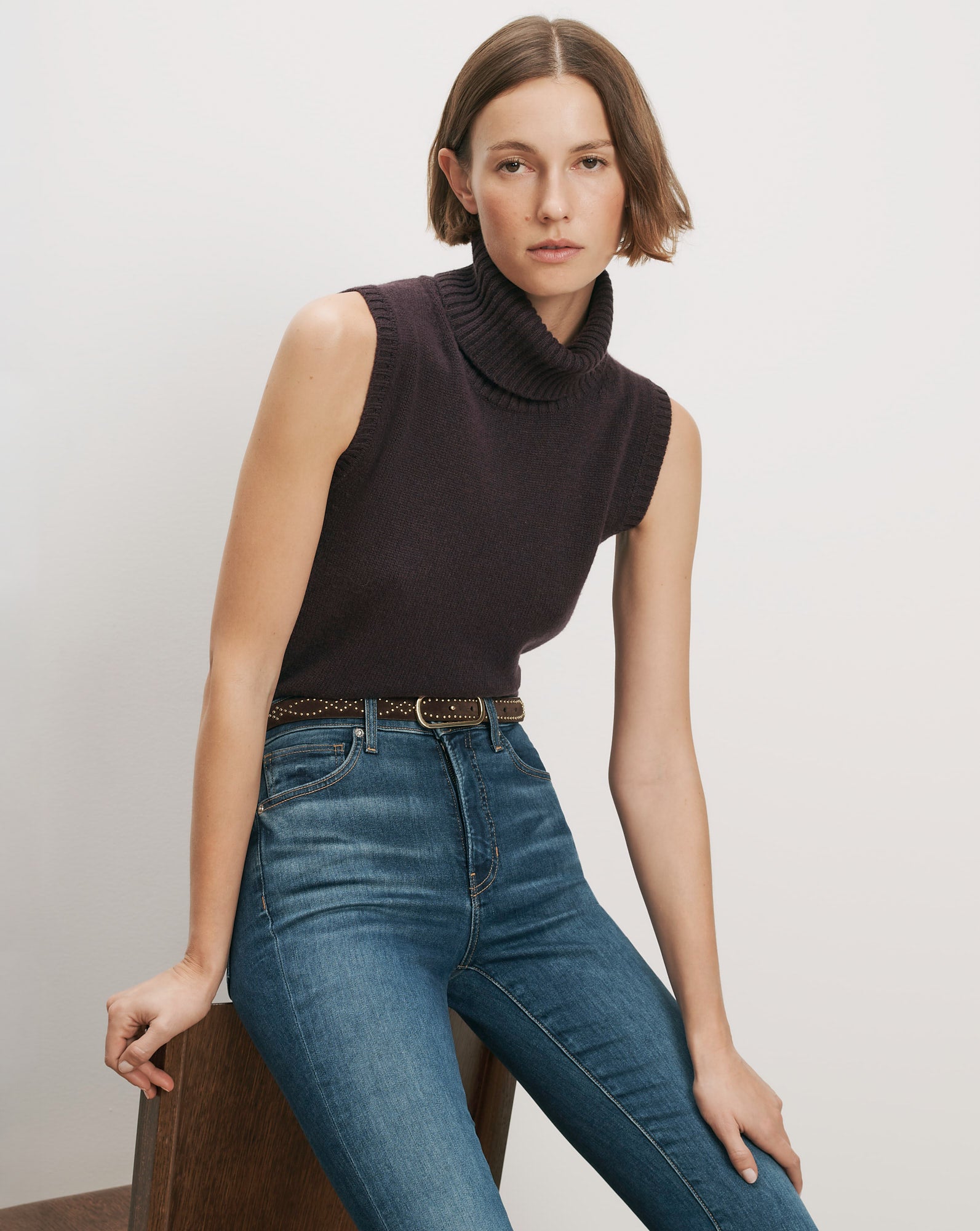 Veronica Beard Brown sleeveless turtleneck sweater, blue jeans, brown belt.