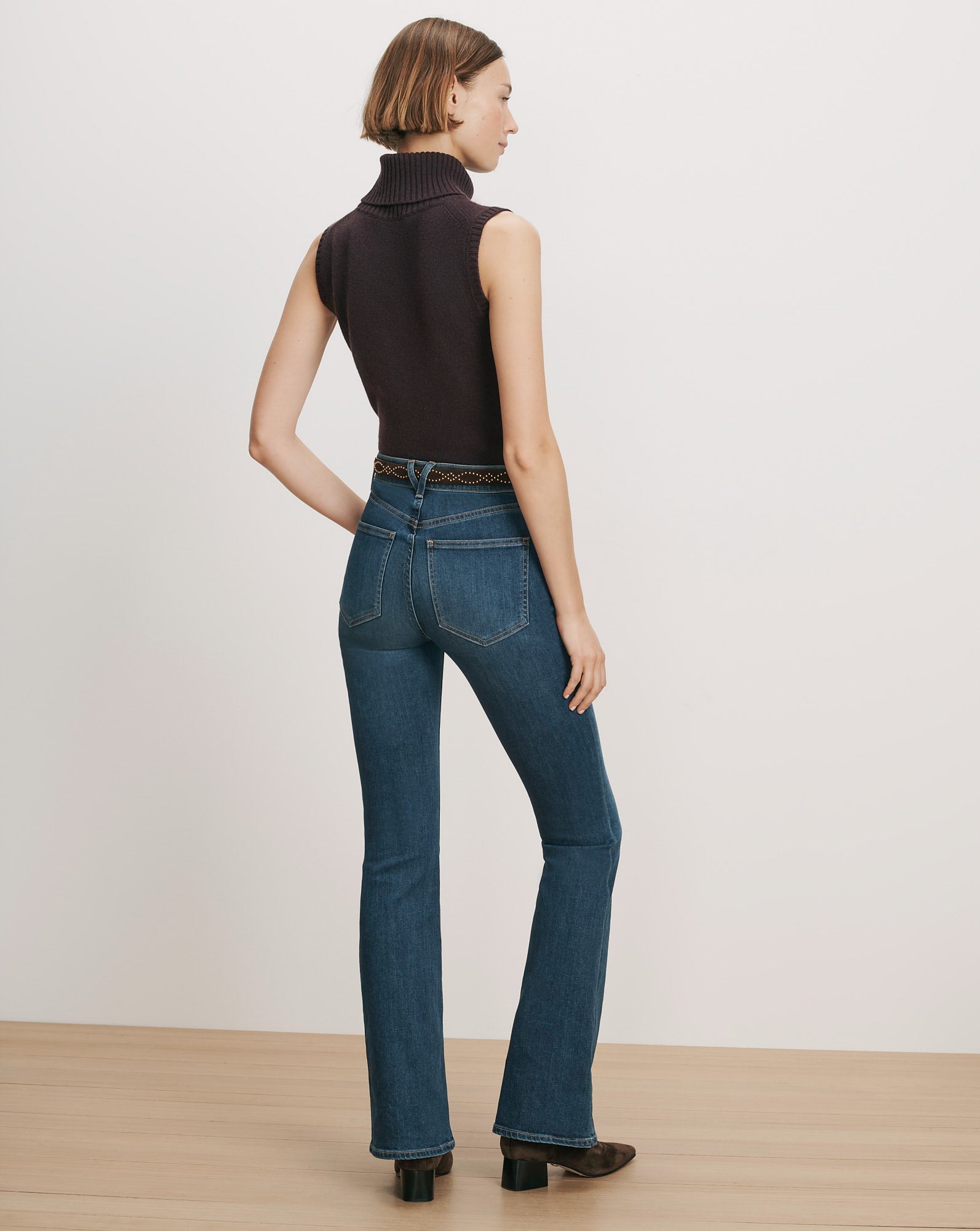 Veronica Beard Dark wash flare jeans with a brown sleeveless turtleneck.