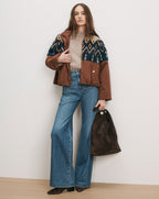 Veronica Beard Brown jacket with patterned yoke, beige sweater, blue jeans, brown bag.