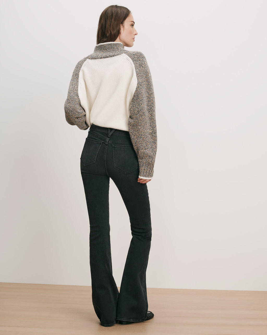 Veronica Beard White and gray knit sweater, black flared jeans.