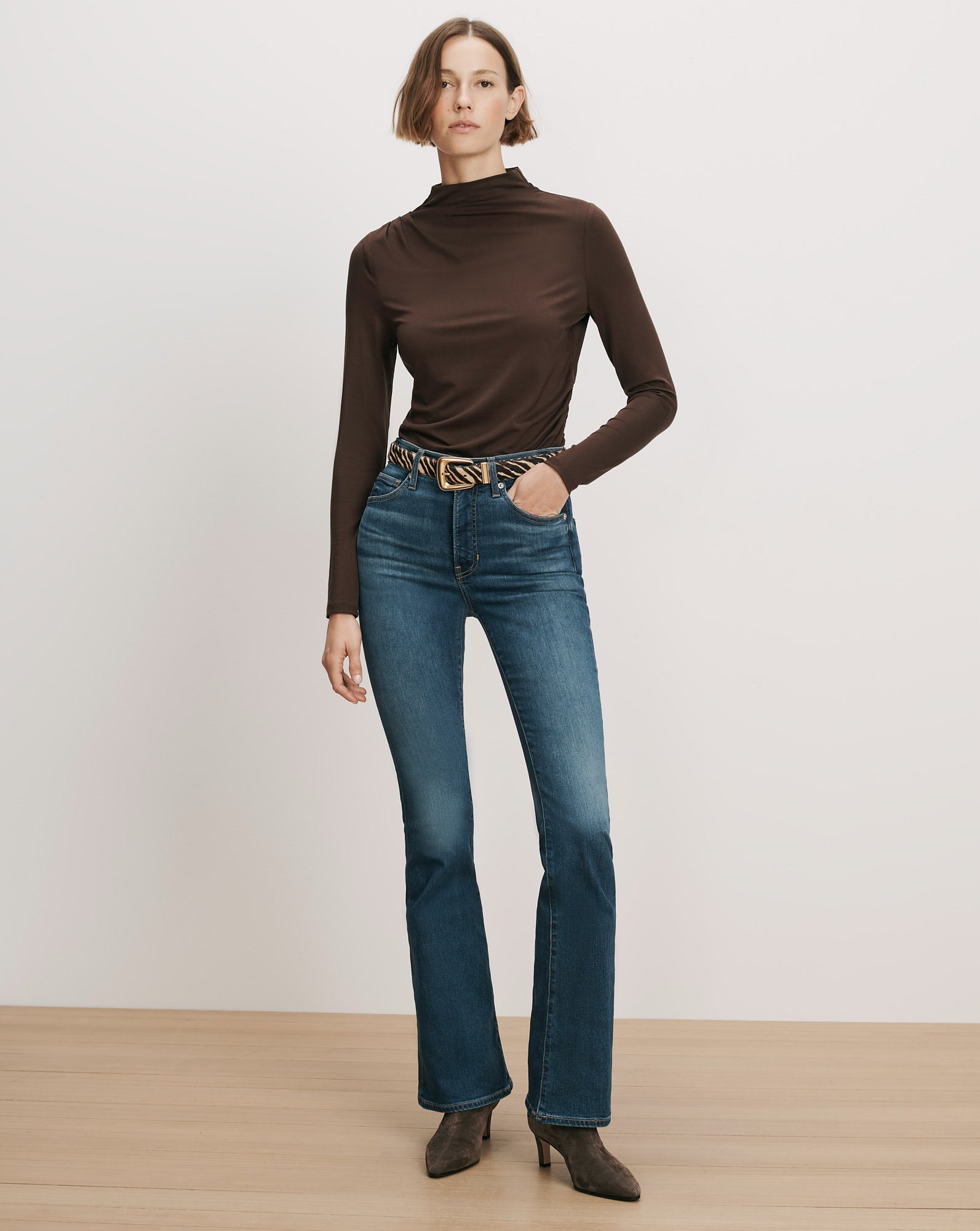 Veronica Beard Brown long-sleeve turtleneck, blue flare jeans, zebra belt.