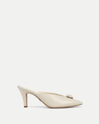 Veronica Beard Cream leather mules with pointed toe and bow detail.