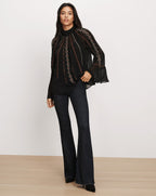 Veronica Beard Black embroidered sheer blouse and flared jeans.