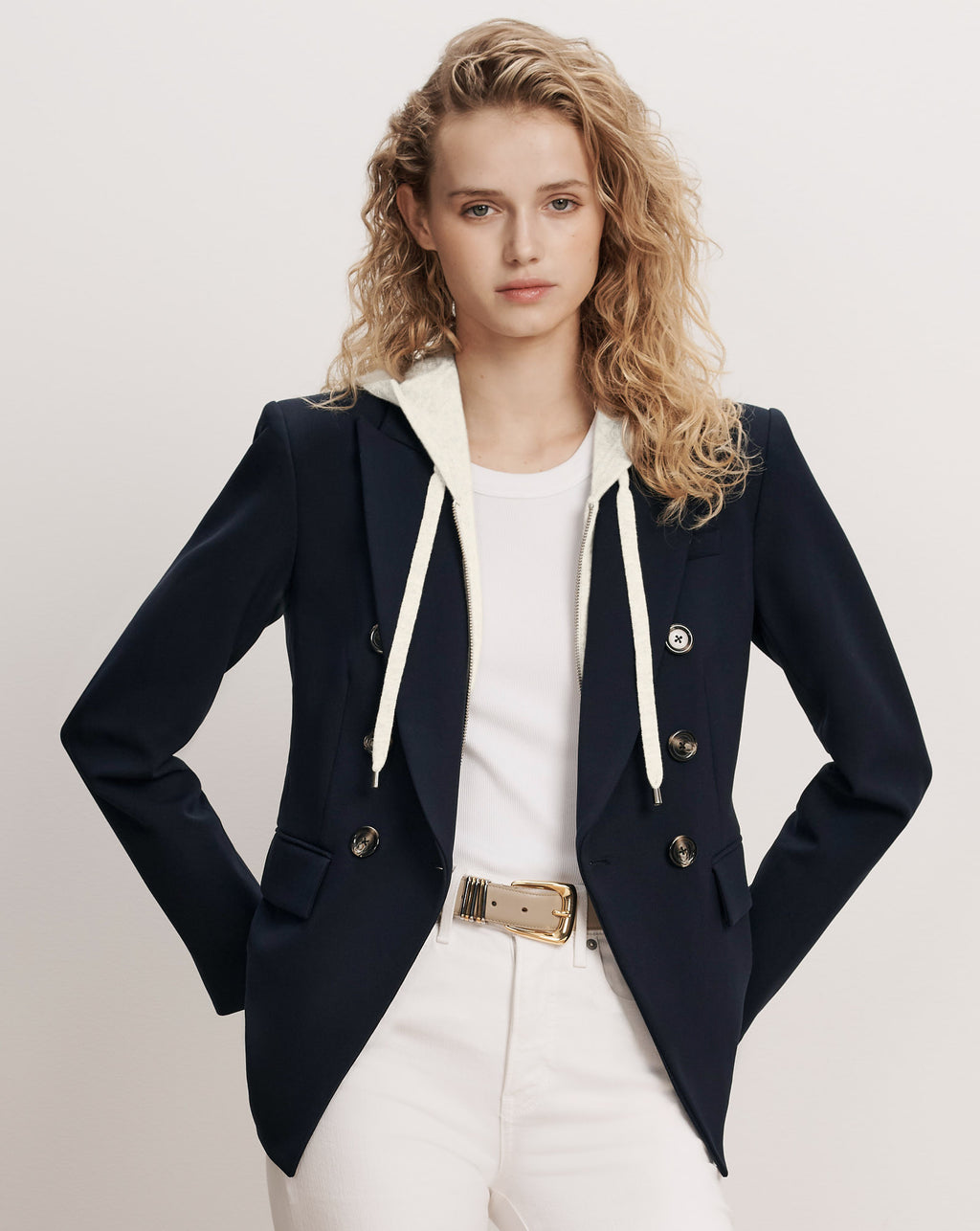 Veronica Beard Navy double-breasted blazer with white hoodie and white pants.