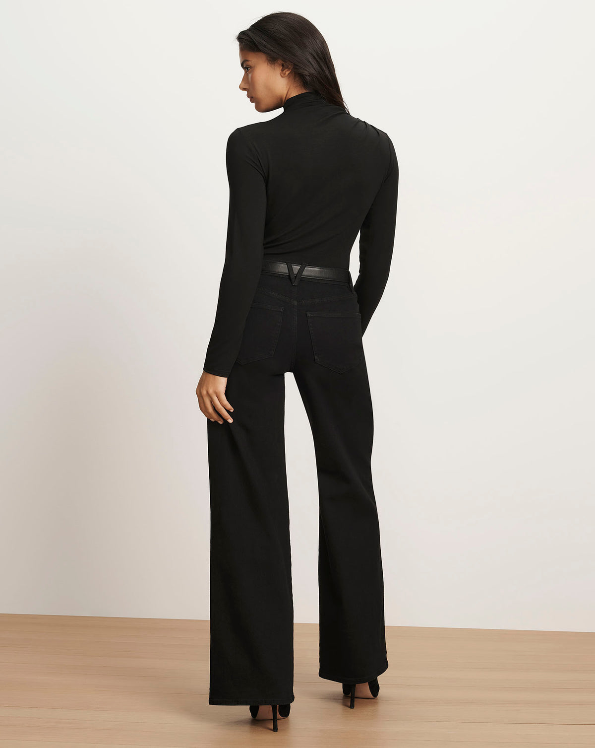 Veronica Beard Black long-sleeve turtleneck top and black wide-leg jeans.