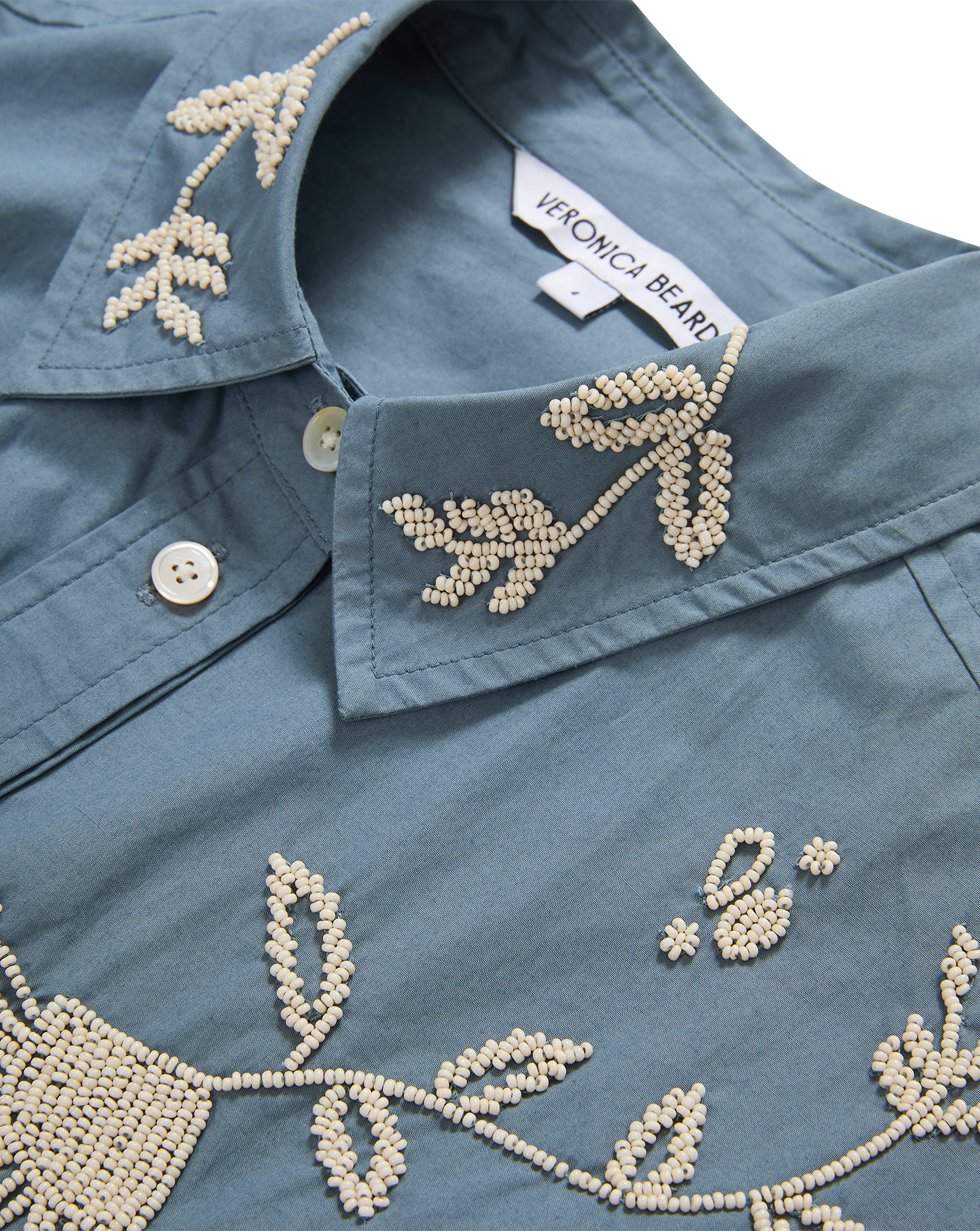Veronica Beard Blue embroidered button-up shirt and cream wide-leg pants.