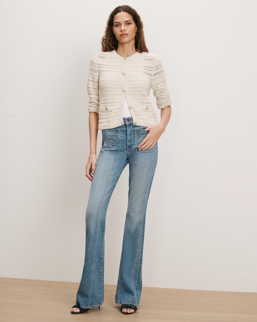 Veronica Beard Cream knit cardigan and blue flared jeans.